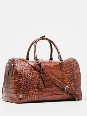 This stunning leather weekend travel bag is perfect for your next getaway. It features a Croco print that adds a touch of luxury and elegance. The roomy interior is perfect for packing all your essentials, and the adjustable strap makes it easy to carry. This classy duffle bag handmade in Italy with Tuscany calf leather and high-quality materials is completed with zipped compartments and card pockets.