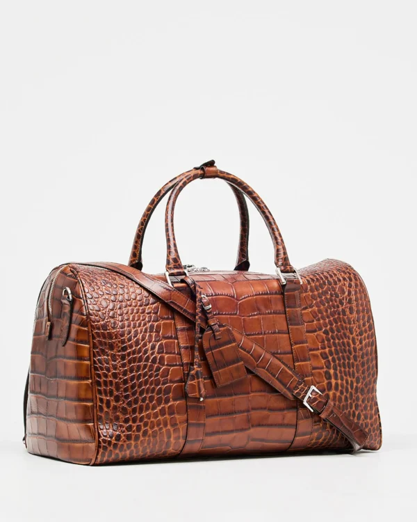 This stunning leather weekend travel bag is perfect for your next getaway. It features a Croco print that adds a touch of luxury and elegance. The roomy interior is perfect for packing all your essentials, and the adjustable strap makes it easy to carry. This classy duffle bag handmade in Italy with Tuscany calf leather and high-quality materials is completed with zipped compartments and card pockets.